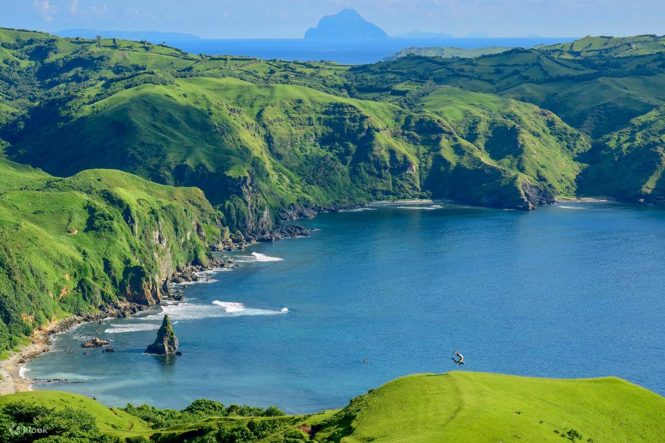 Aerial view of Vayang Rolling Hills sweeping down to the West Philippine Sea at golden hour in Batanes